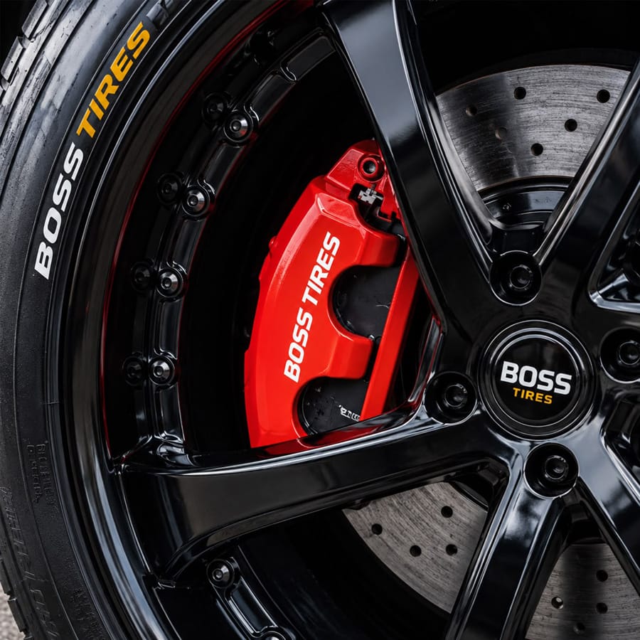 A Boss Tire branded red brake caliper behind a black alloy wheel