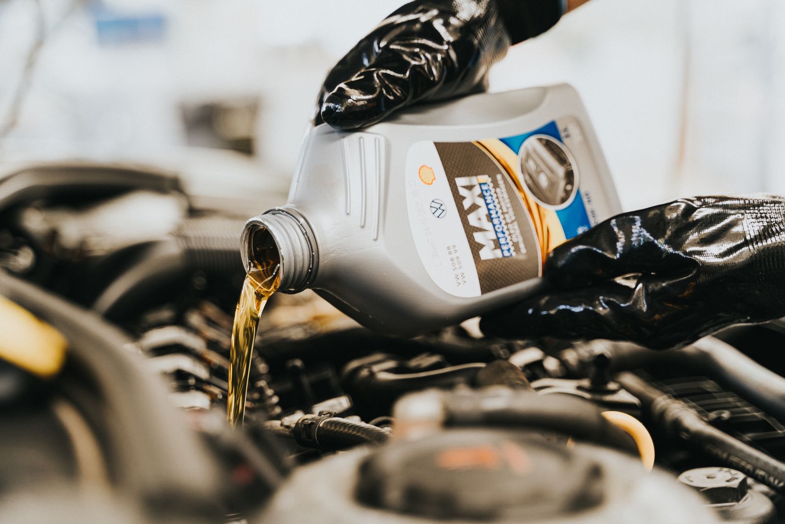A mechanic pouring fresh engine oil into a car engine