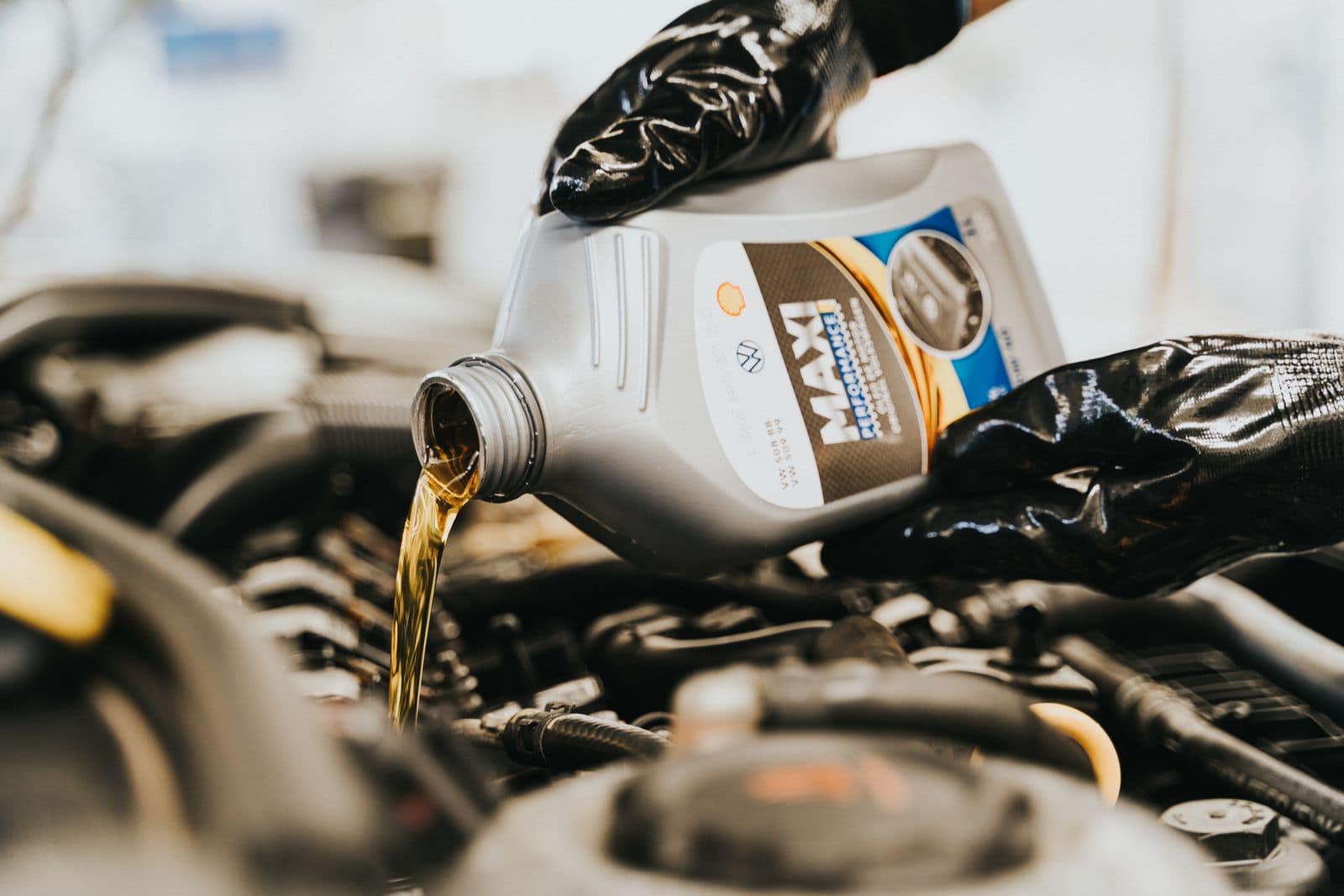 A mechanic pouring fresh engine oil into a car engine